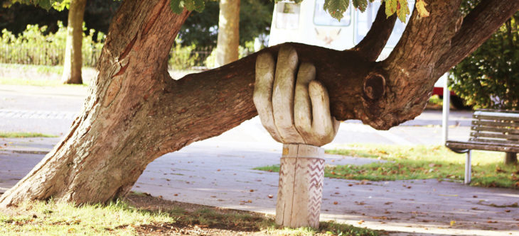 Holzhand stützt schiefen Baum