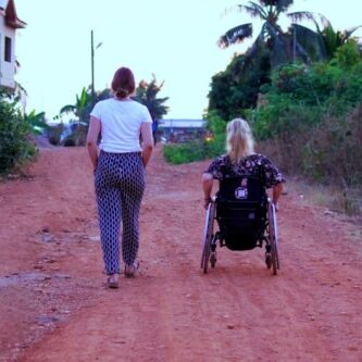 Eine Fußgängerin und eine Rollstuhlfahrerin sind gemeinsam unterwegs